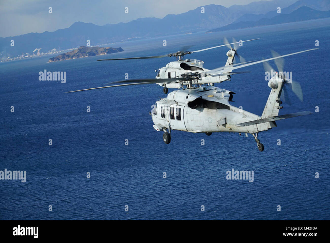 HIROSHIMA, Japan (Jan. 25, 2018) U.S. Navy MH-60R and MH-60S Seahawk helicopters, assigned to Helicopter Maritime Strike Squadron (HSM) 51 and Helicopter Sea Combat Squadron (HSC) 25 rendezvous off the coast of Hiroshima following a Strike Coordination and Reconnaissance training mission from Marine Corps Air Station Iwakuni. Forward-deployed to Naval Air Facility Atsugi, HSC 25’s Detachment 6 conducted several training while in Iwakuni to meet with F-35B Joint Strike Fighter pilots of Marine Fighter Attack Squadron 121 (VMFA-121). The flights with HSM 51 were meant to enhance surface warfare  Stock Photo