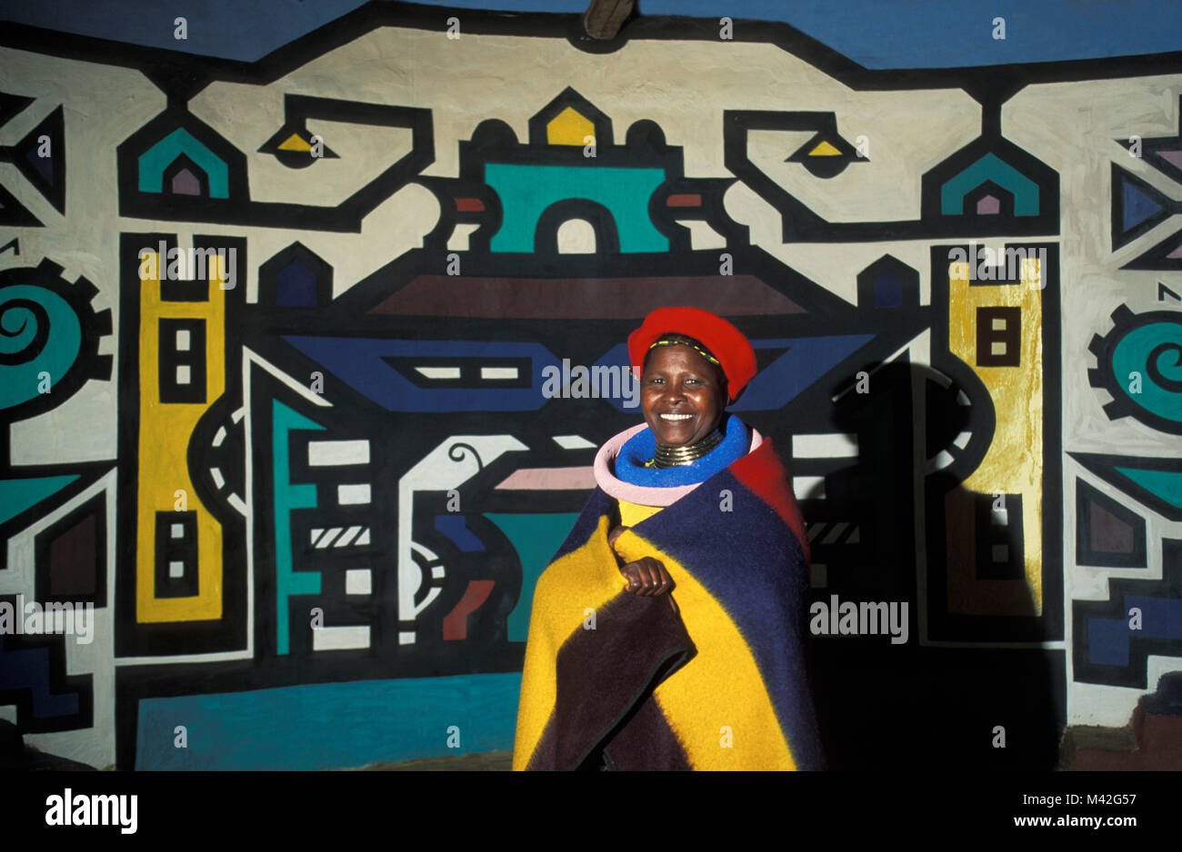South Africa. Mapoch Ndebele Village, near Pretoria. traditional wall paintings of Ndebele tribe. Woman with traditional clothing. Stock Photo