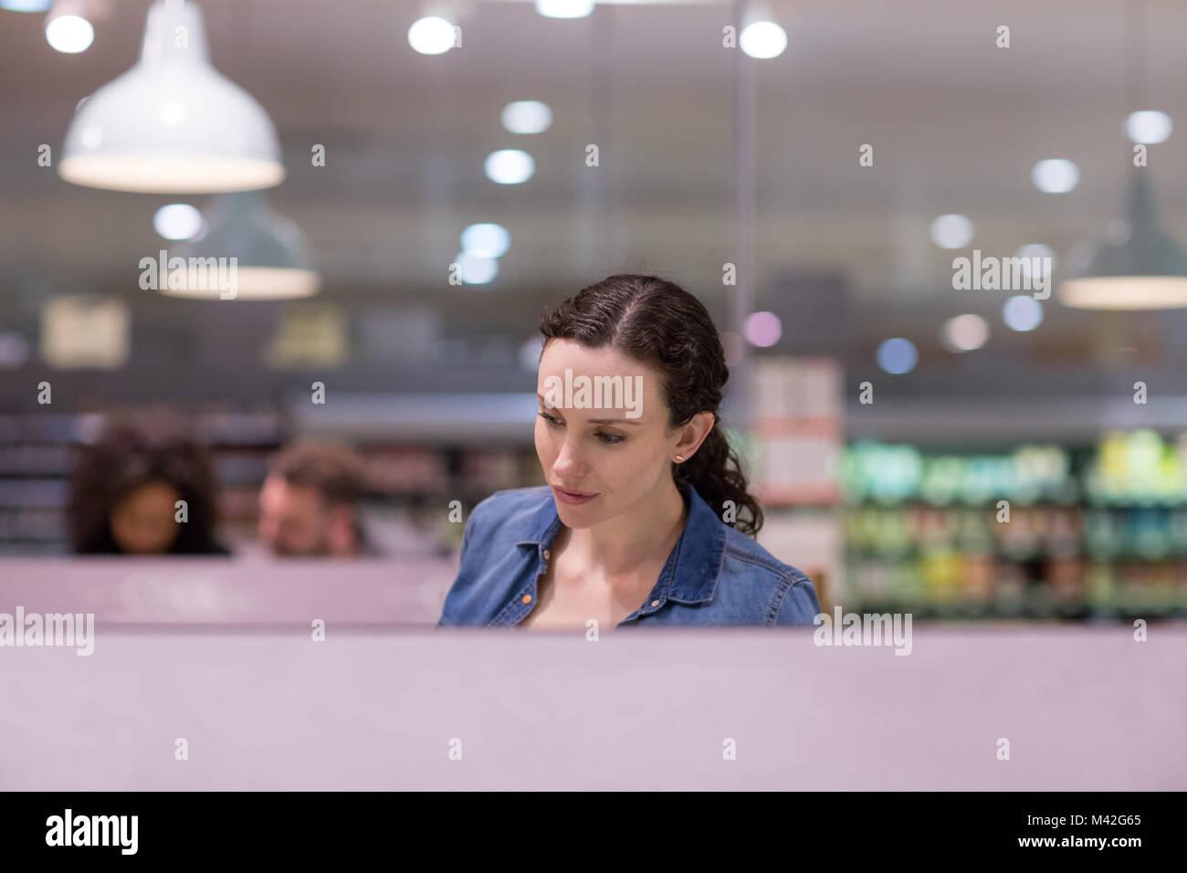 Woman looking at ready meal in grocery store Stock Photo