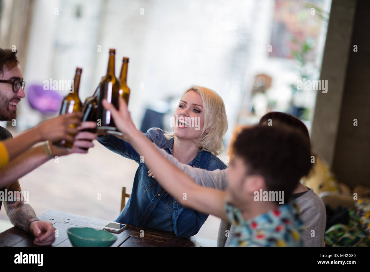 Group of friends clinking beer bottles at a house party Stock Photo