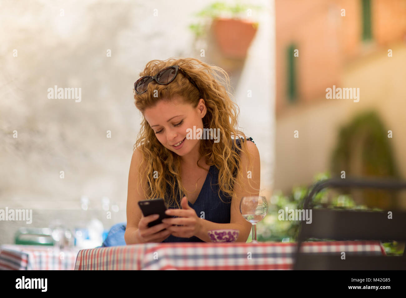 Young adult female sitting at café with smartphone Stock Photo