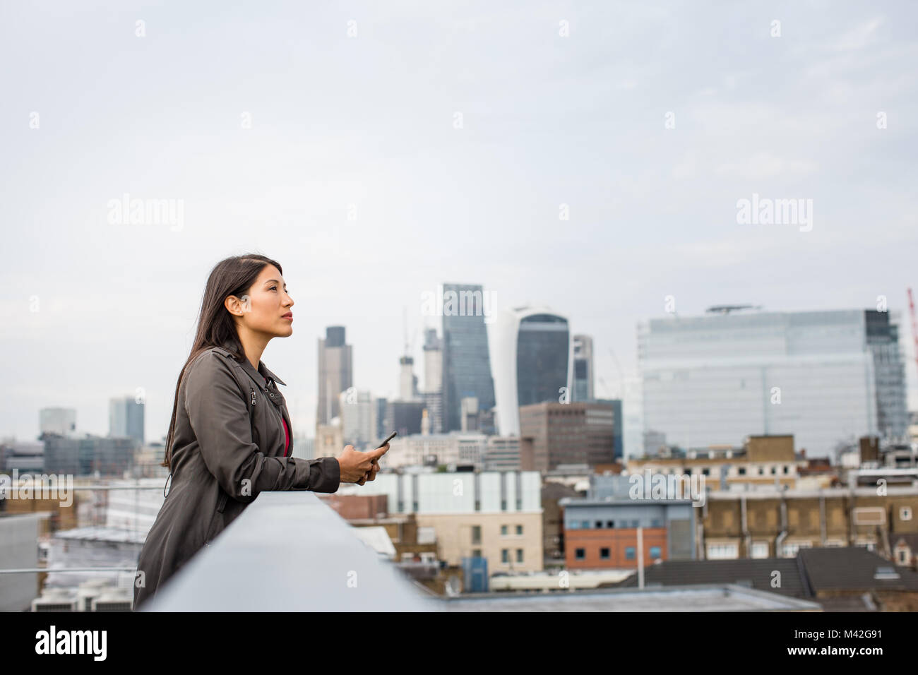 Businesswoman looking out at London city skyline Stock Photo