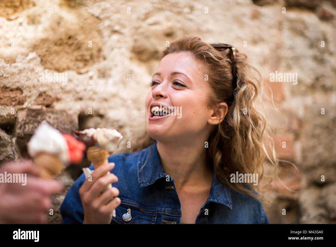 Young female eating gelato with friend Stock Photo