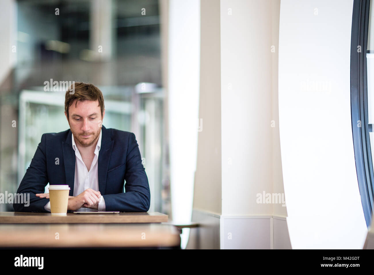 Businessman in a café reading a digital tablet Stock Photo