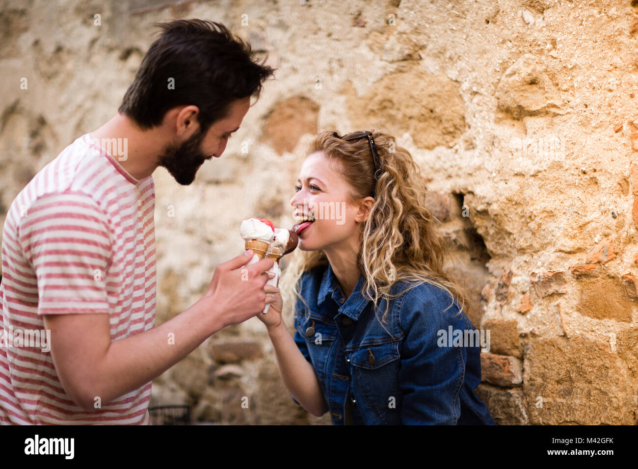 Young female eating gelato with boyfriend Stock Photo