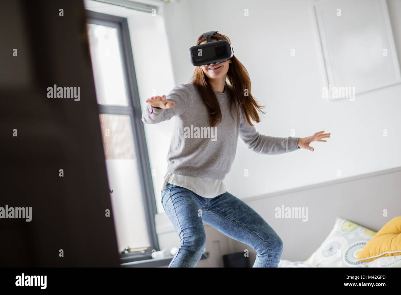 Young adult female learning to surf with VR headset Stock Photo