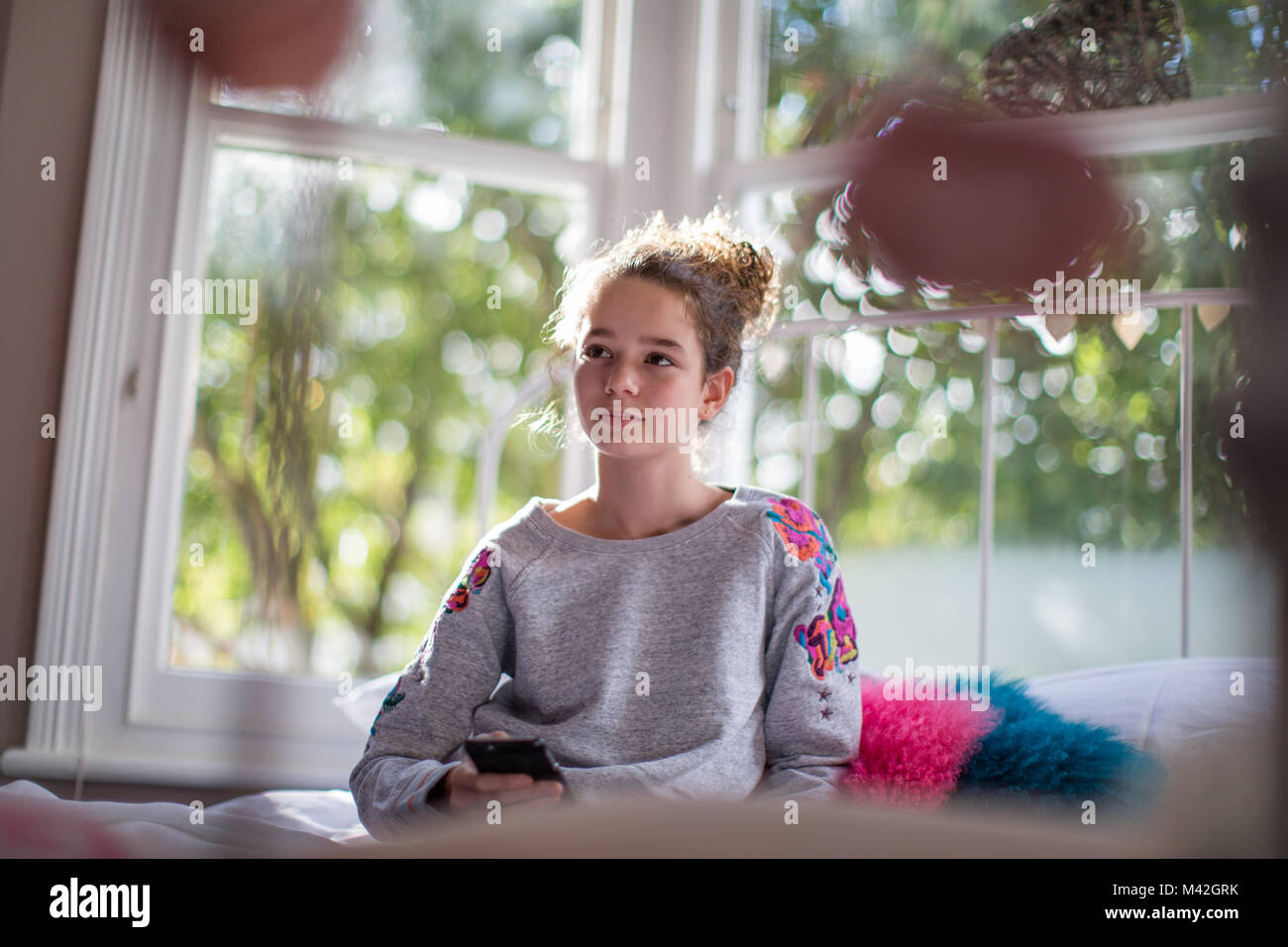 Teenager in bedroom holding smartphone Stock Photo