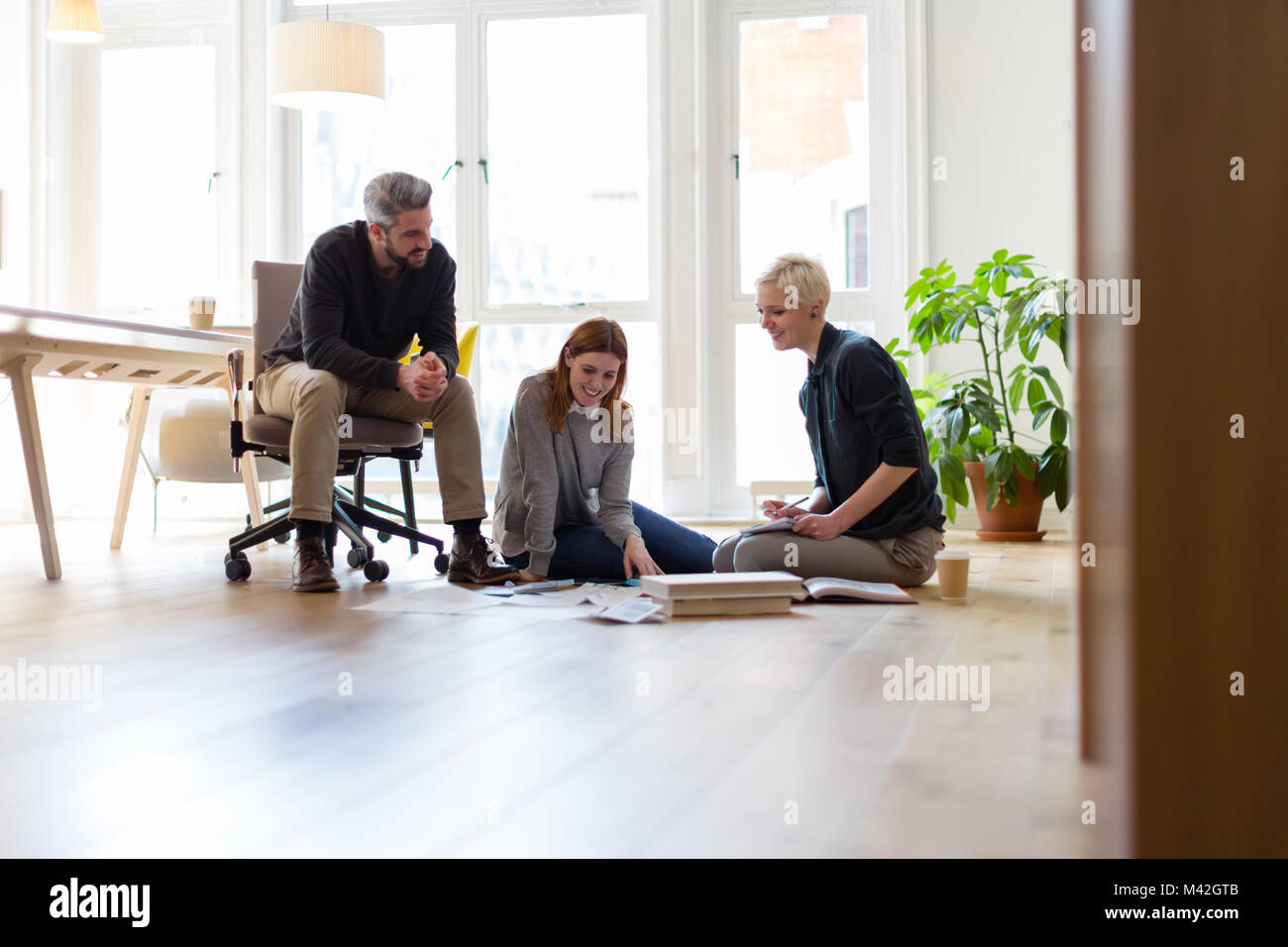Group of designers discussing ideas with paperwork on office floor Stock Photo