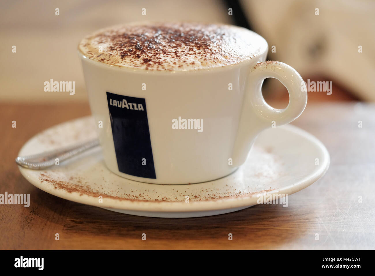 A freshly brewed cup of Lavazza coffee, with a thick crema and chocolate dusting. Served in a Lavazza branded coffee cup clearly showing the logo Stock Photo