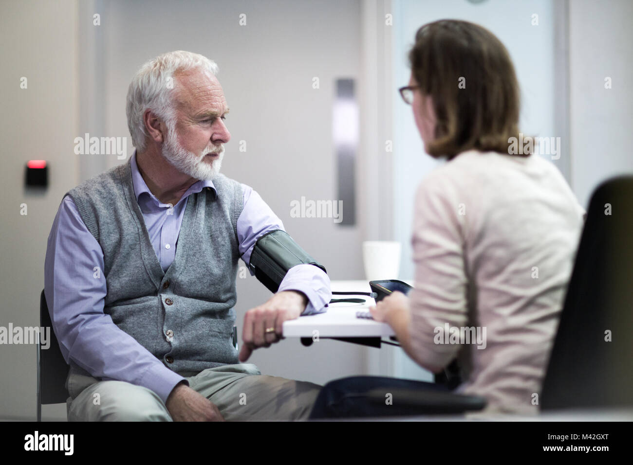 Female Medical Doctor taking a Senior patients blood pressure Stock Photo