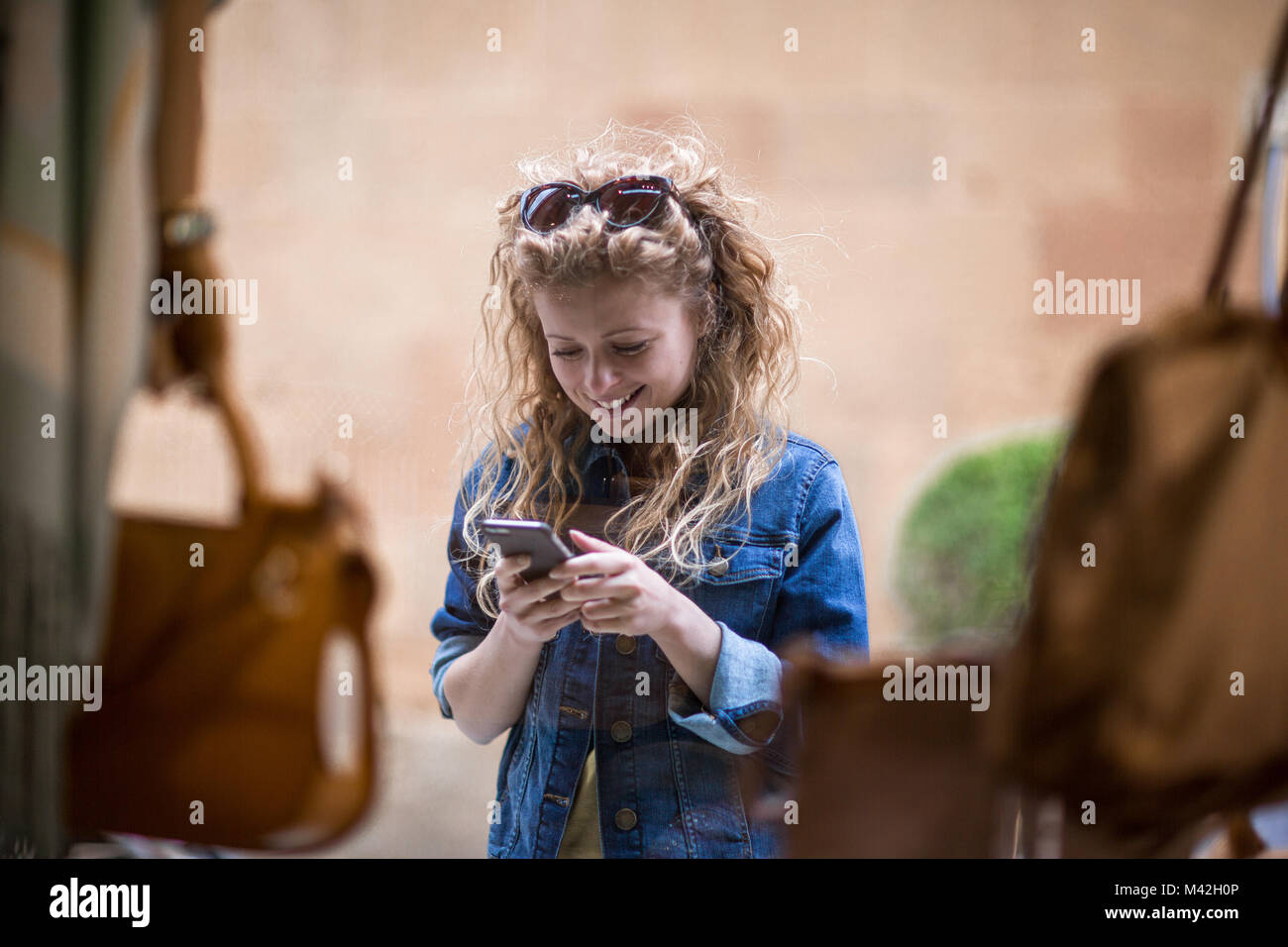Young female window shopping and using smartphone Stock Photo