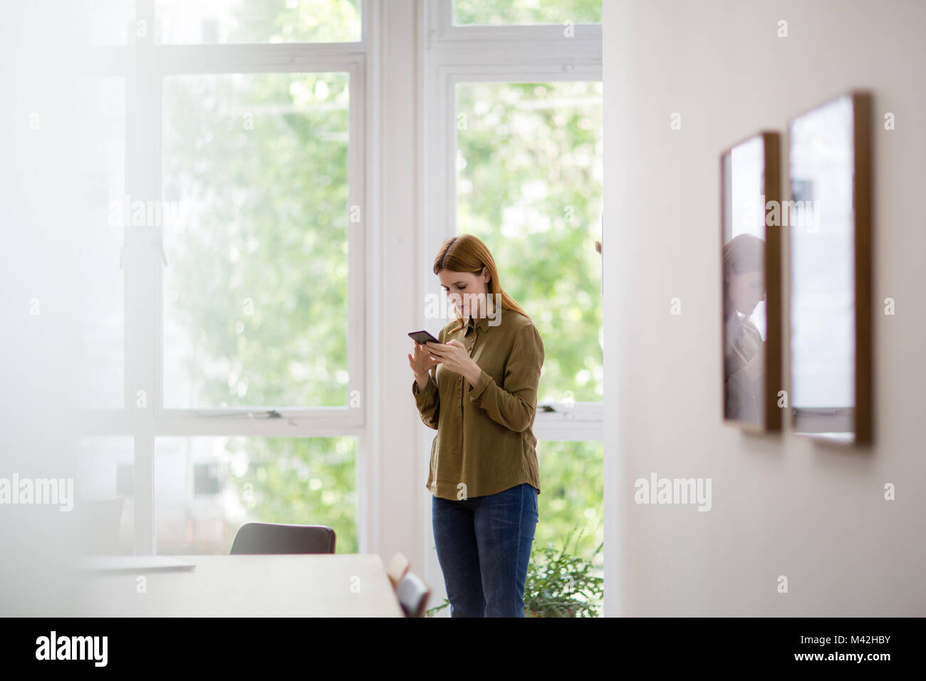 Businesswoman in empty office looking at smartphone Stock Photo
