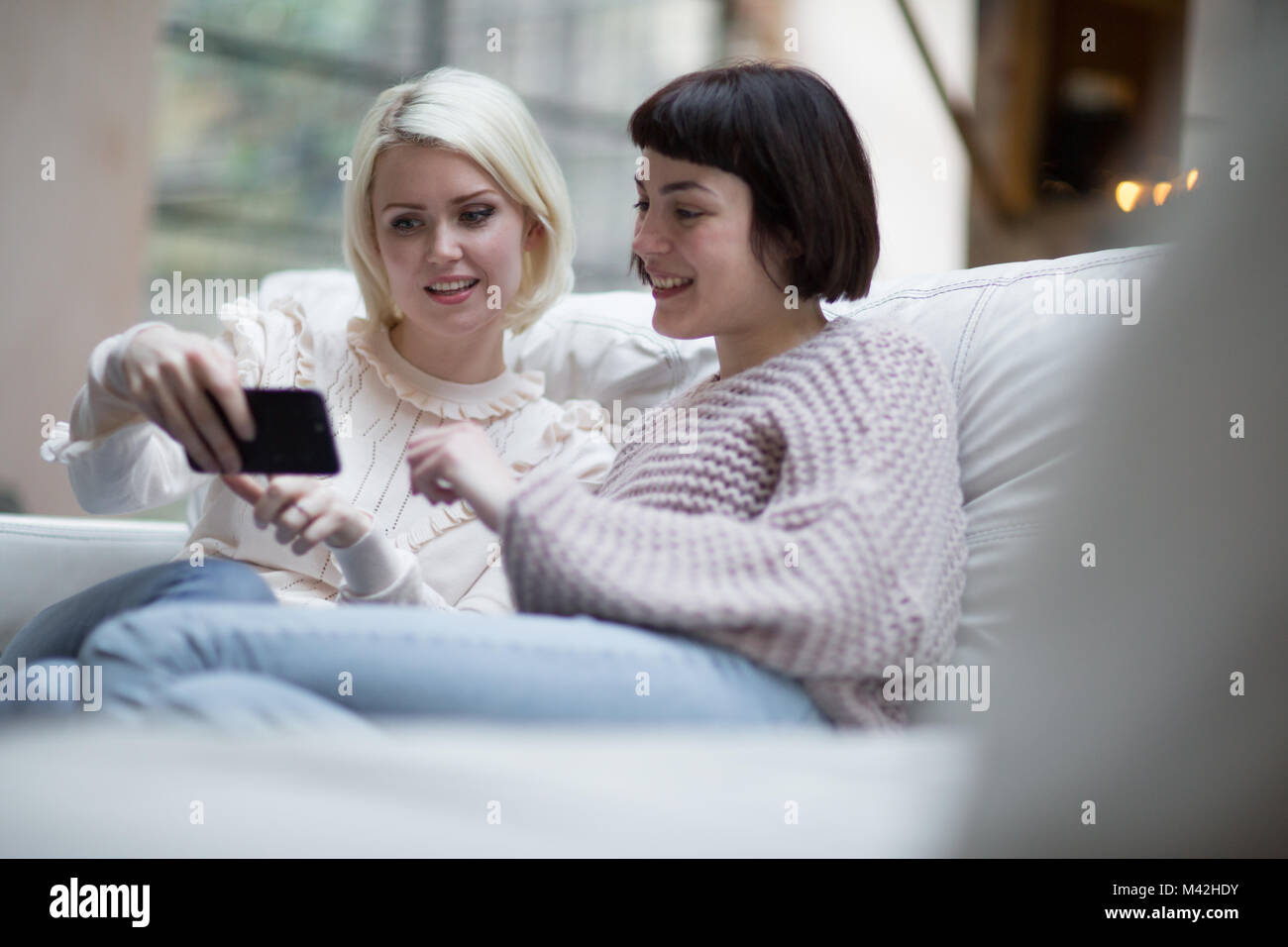 Young adult female friends watching video on smartphone Stock Photo