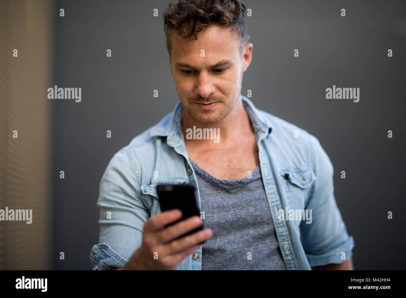 Young adult walking down street checking smartphone Stock Photo