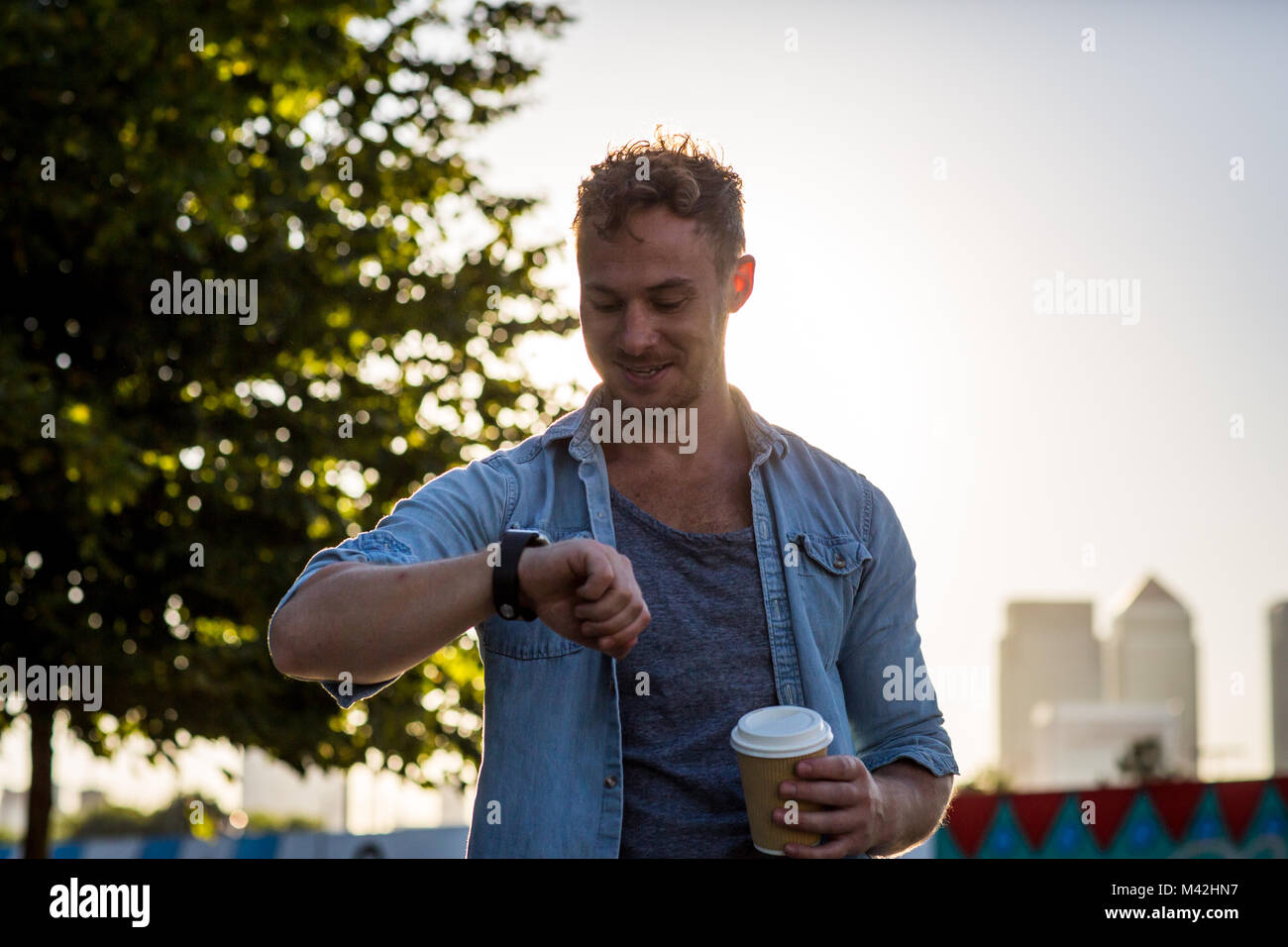 Young adult walking down street using smartwatch Stock Photo