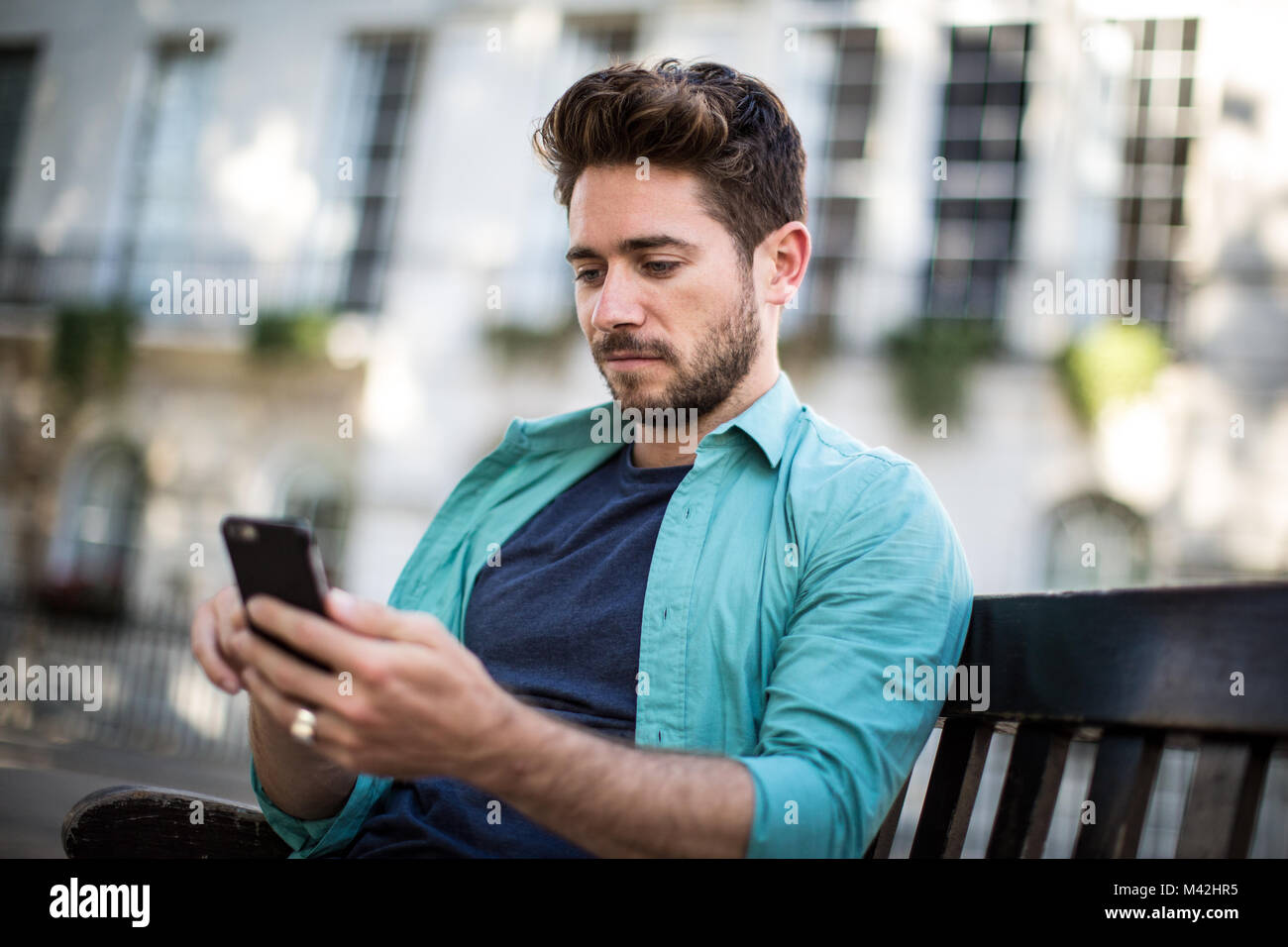 Tourist sitting on bench in London looking at smartphone Stock Photo