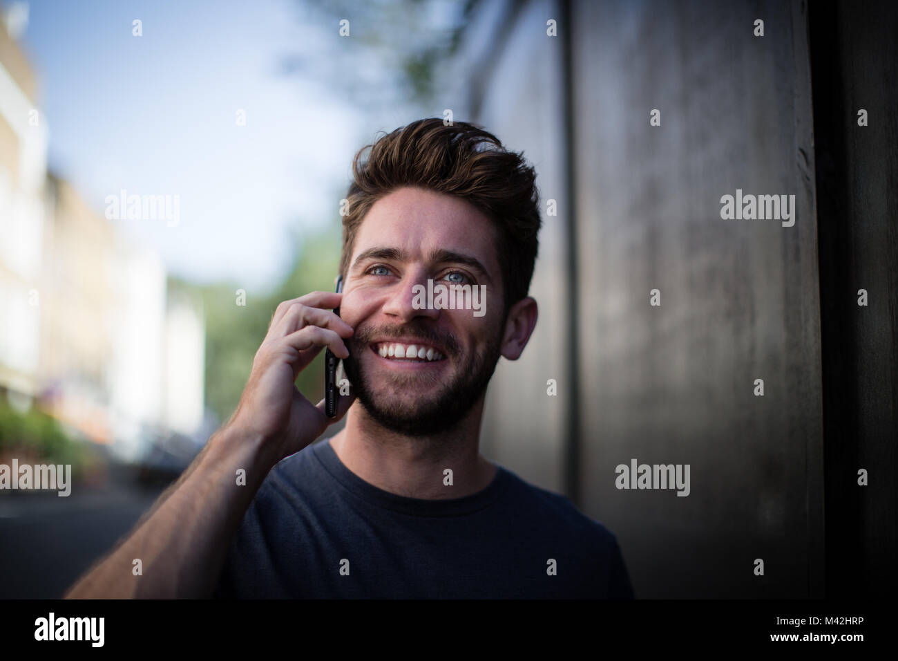 Young adult walking down street on phone Stock Photo