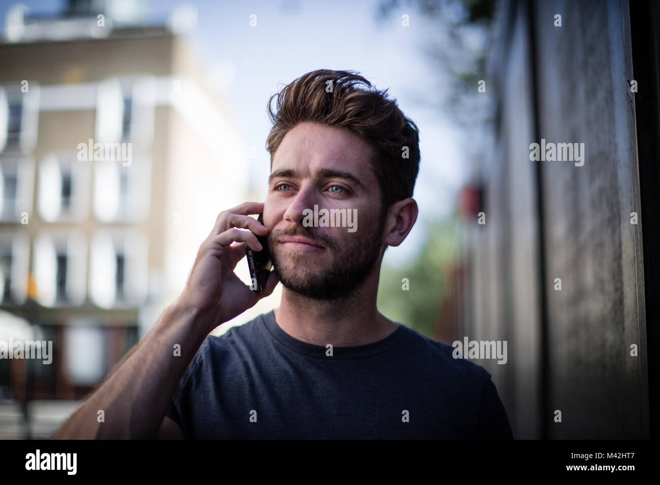 Young adult walking down street on phone Stock Photo