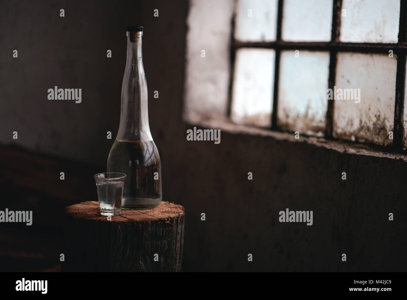 Strong alcohol drink in bottle with shot glass in traditional rustic retro toned atmosphere Stock Photo