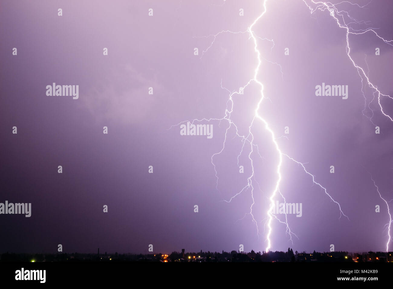A huge and beautiful discharge of lightning in a stormy sky over a small town Stock Photo