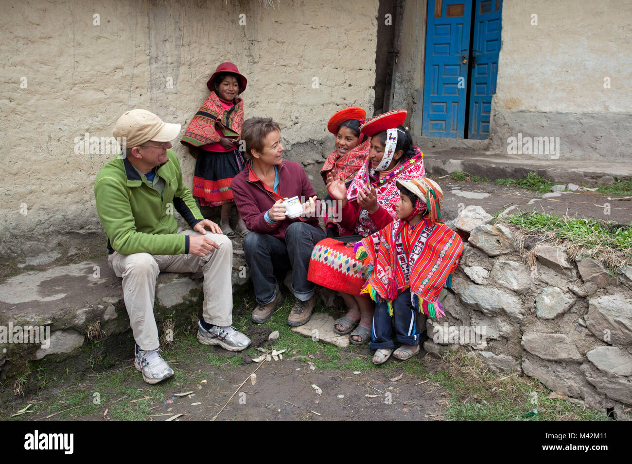 Peru, Patakancha, Patacancha, village near Ollantaytambo. Indian family in traditional dress and tourists, man and woman, conversation. Stock Photo