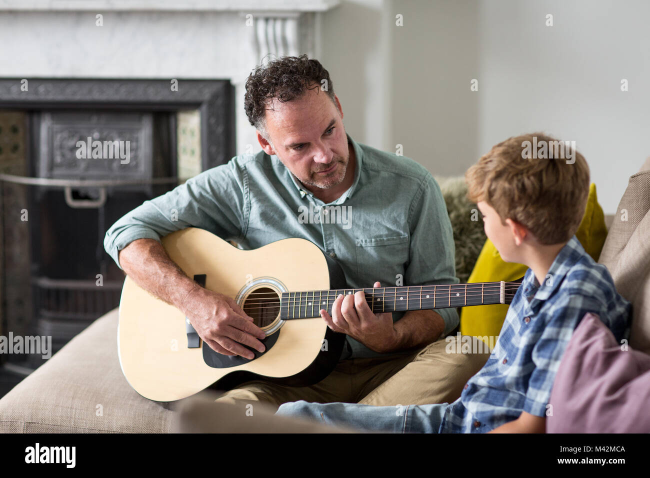 Father teaching son how to play guitar Stock Photo