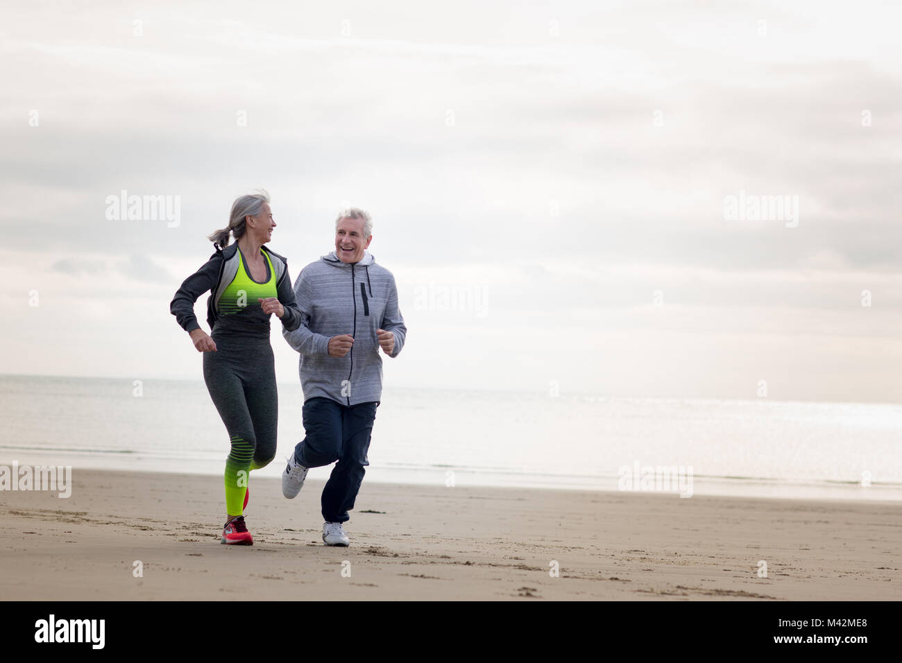 Senior couple jogging on beach Stock Photo