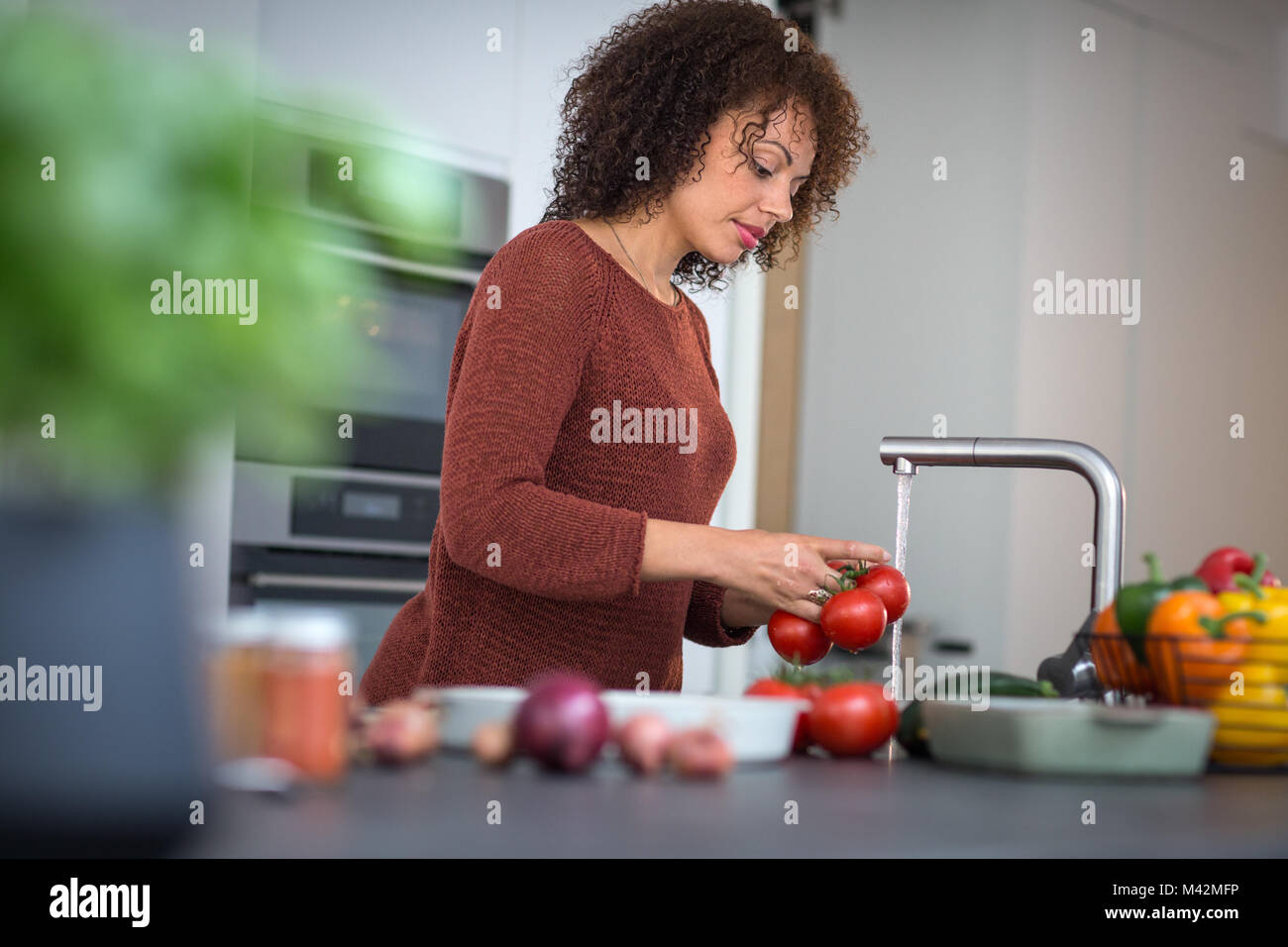 African American female washing tomatoes Stock Photo