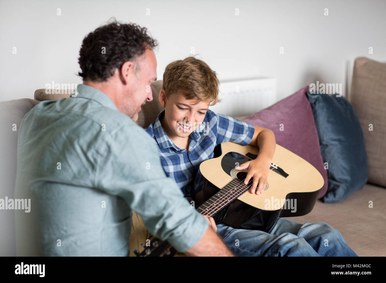 Son playing guitar with Father Stock Photo