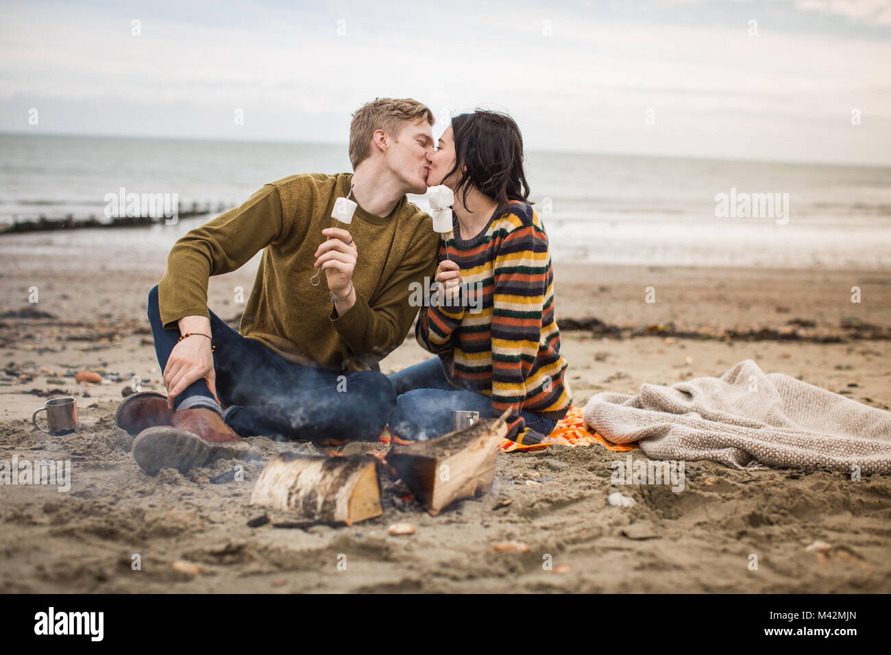 Young couple kissing by camp fire Stock Photo