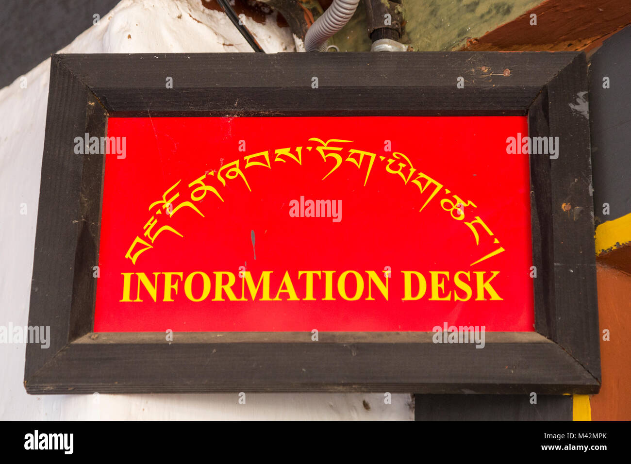 Punakha, Bhutan.  Bilingual Sign, English and Dzongkha, in Tibetan Alphabet.  Information Desk. Stock Photo