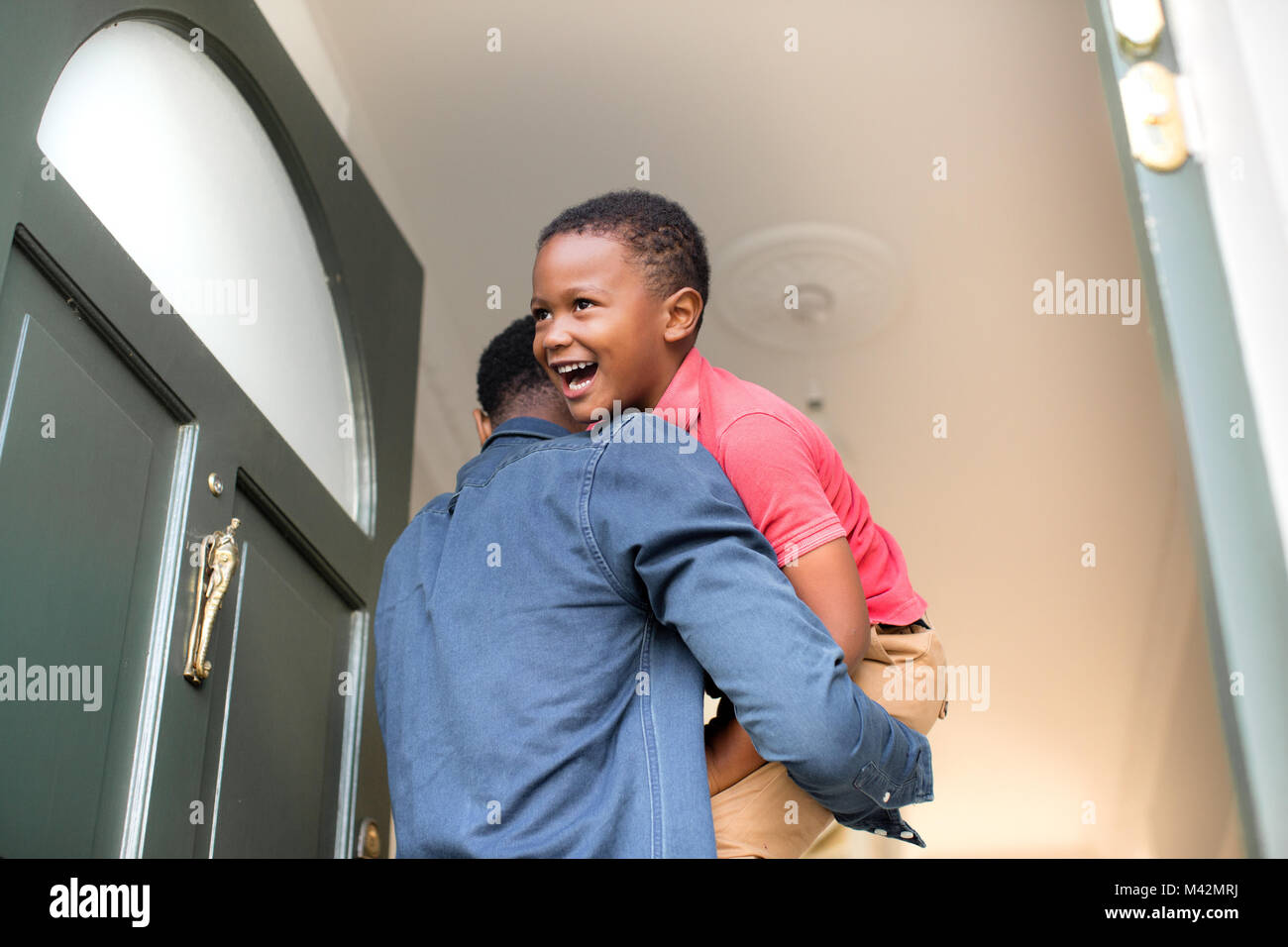 Dad carrying son into family home Stock Photo