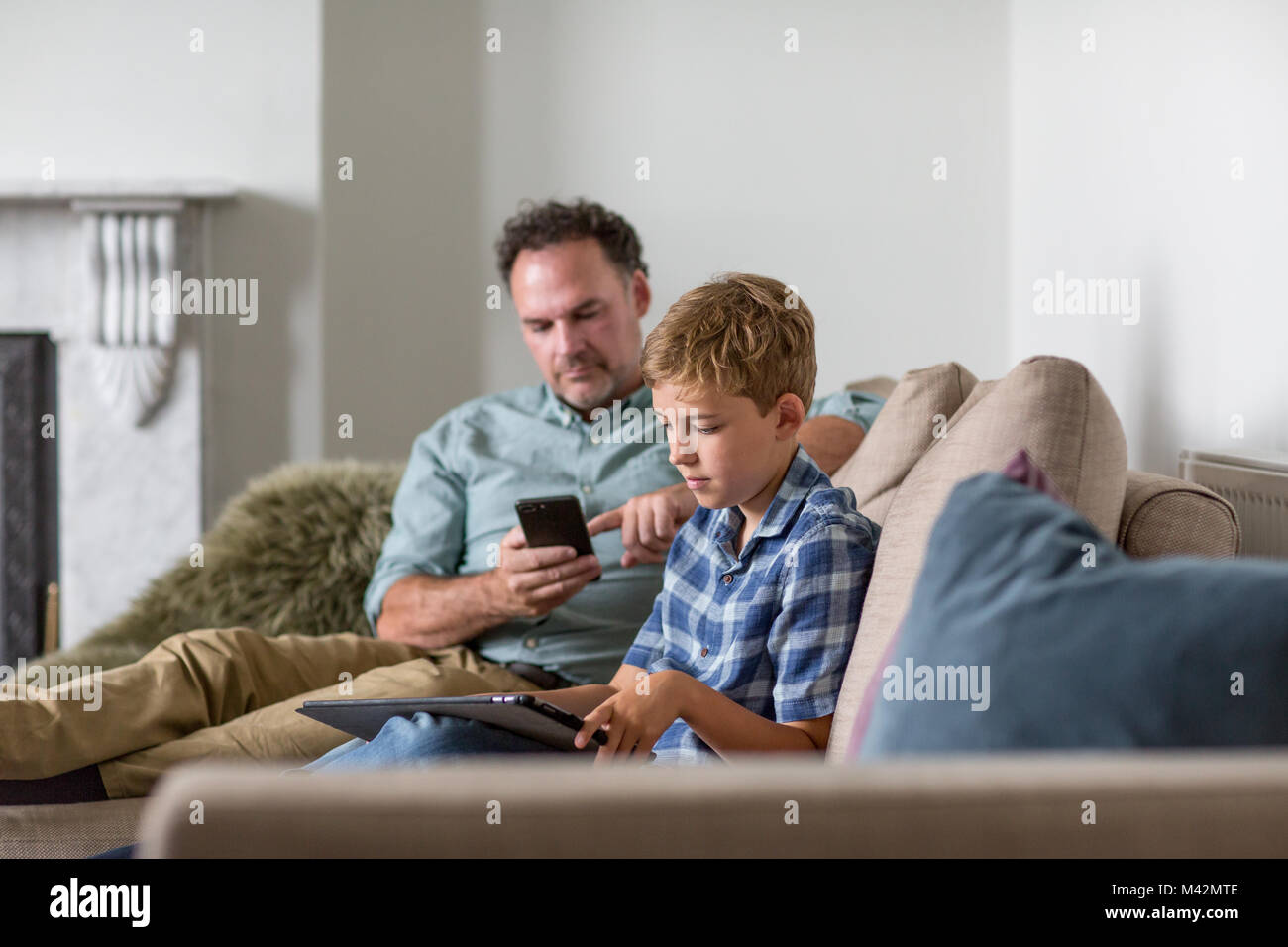 Father and Son individually using technology Stock Photo