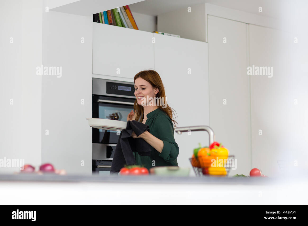 Adult female taking dish out of oven Stock Photo