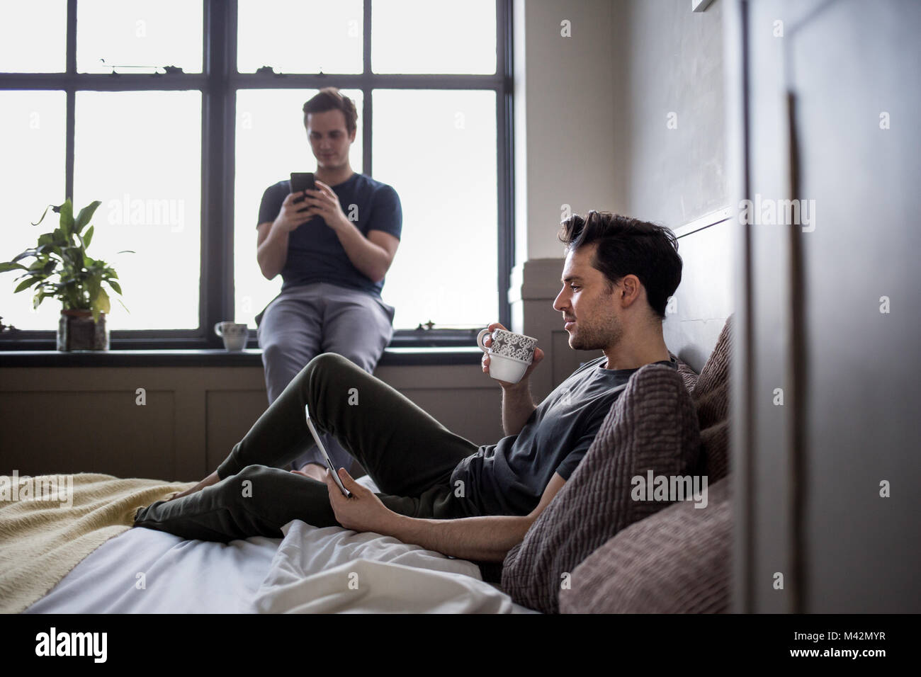 Young male couple on personal devices Stock Photo