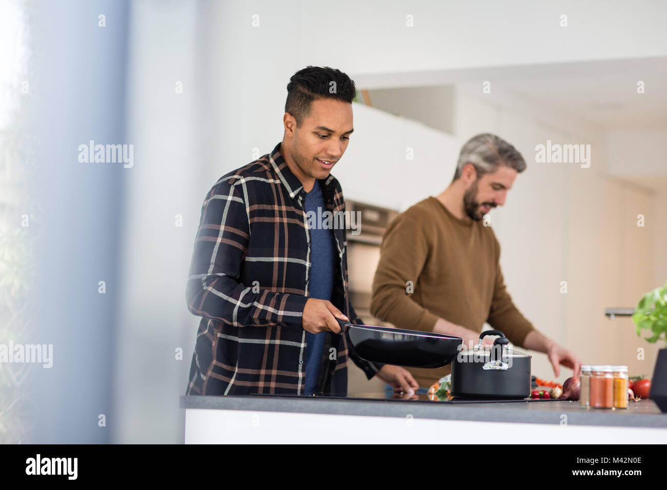 Adult male friends preparing a meal together Stock Photo
