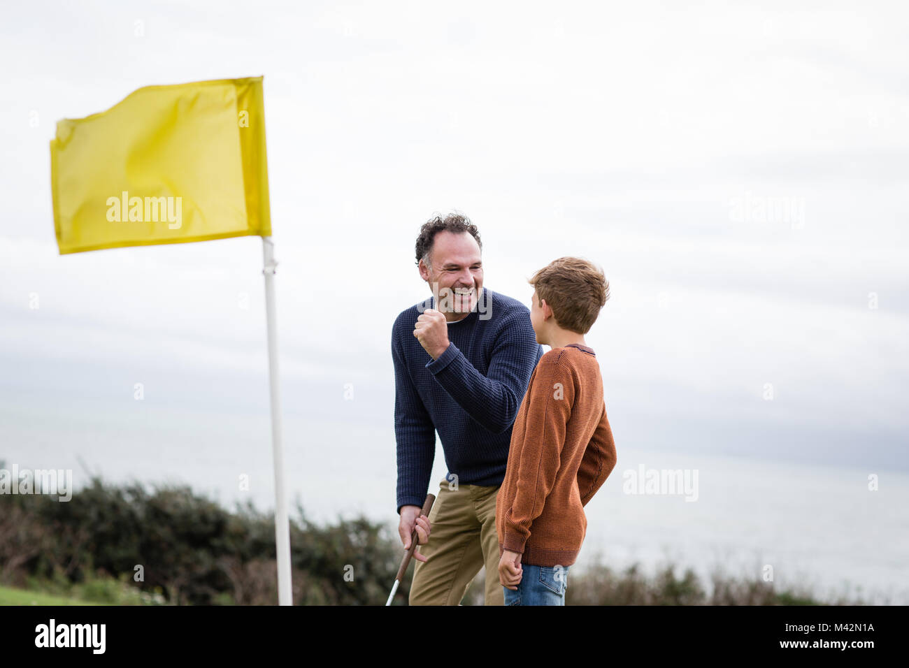 Father celebrating with son on golf course Stock Photo