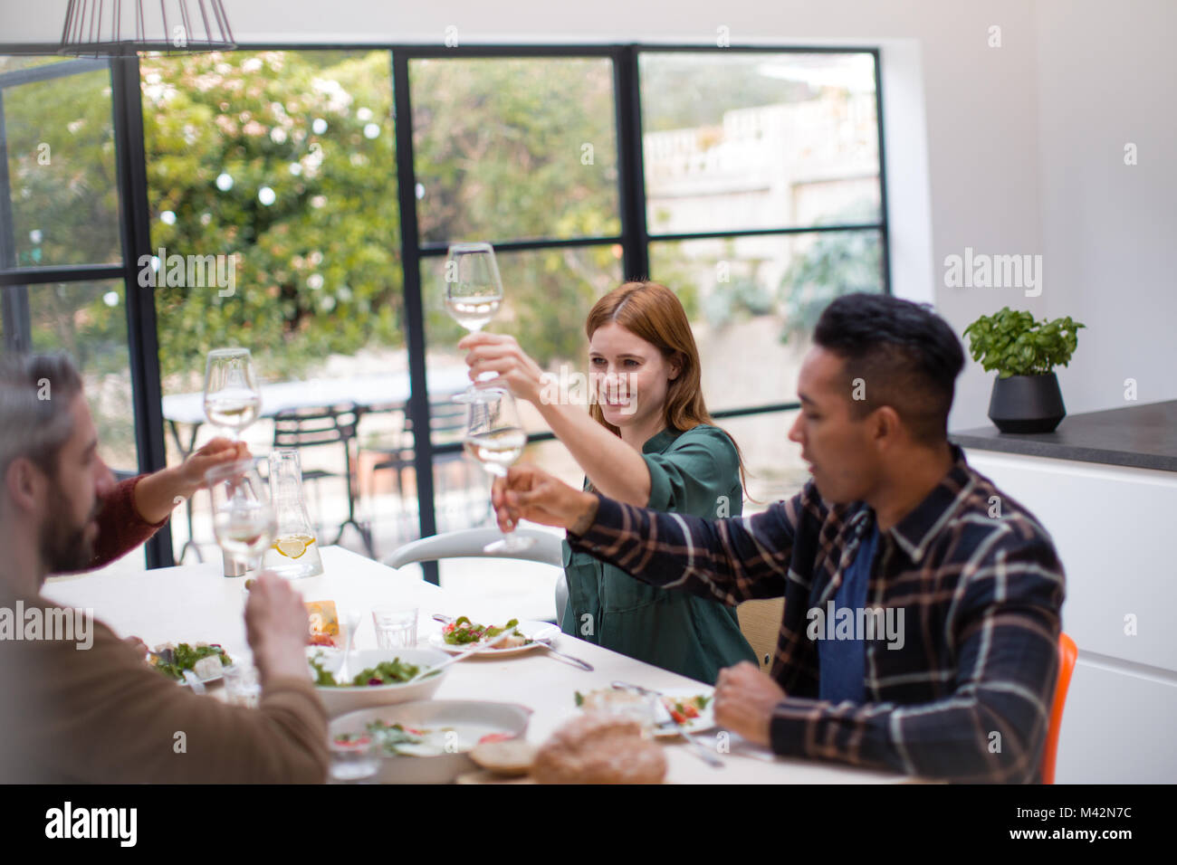 Friends clinking glasses over a meal together Stock Photo