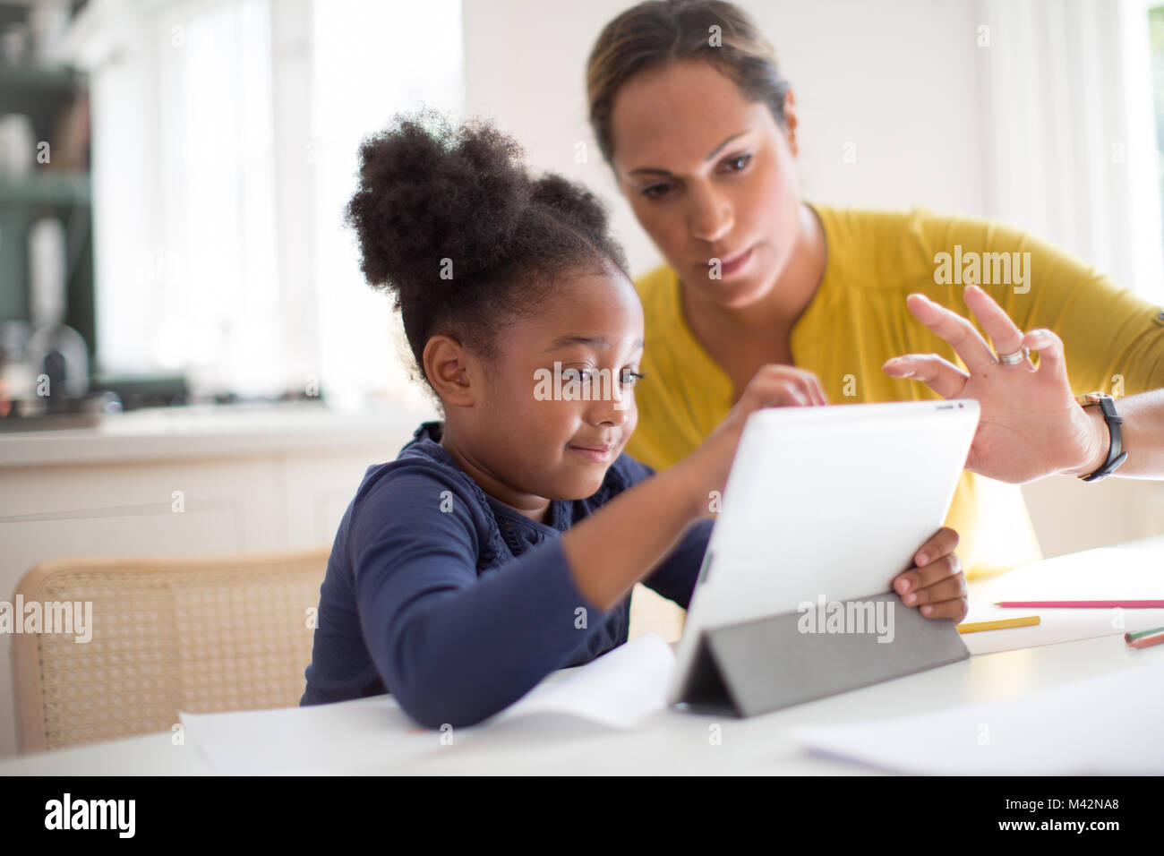 Mother teaching Daughter how to use digital tablet Stock Photo
