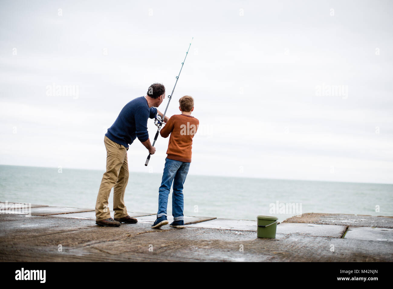 Father helping Son fish Stock Photo