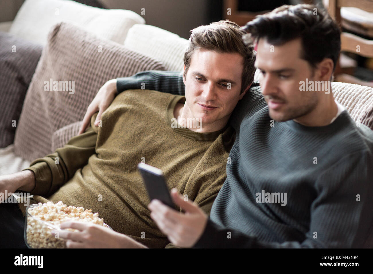 Young male couple relaxing on sofa streaming entertainment Stock Photo