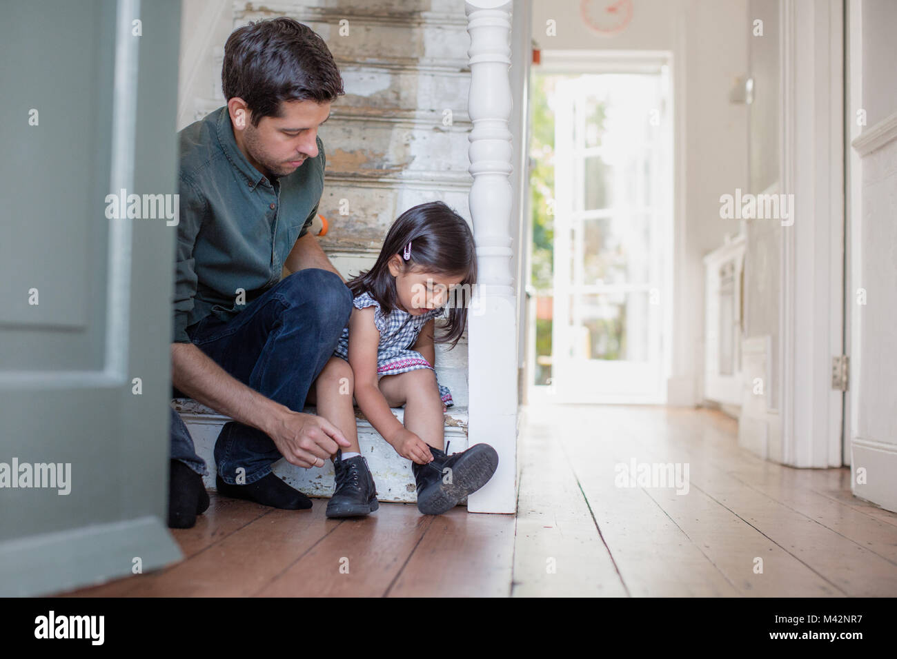 Dad helping daughter with her shoes Stock Photo
