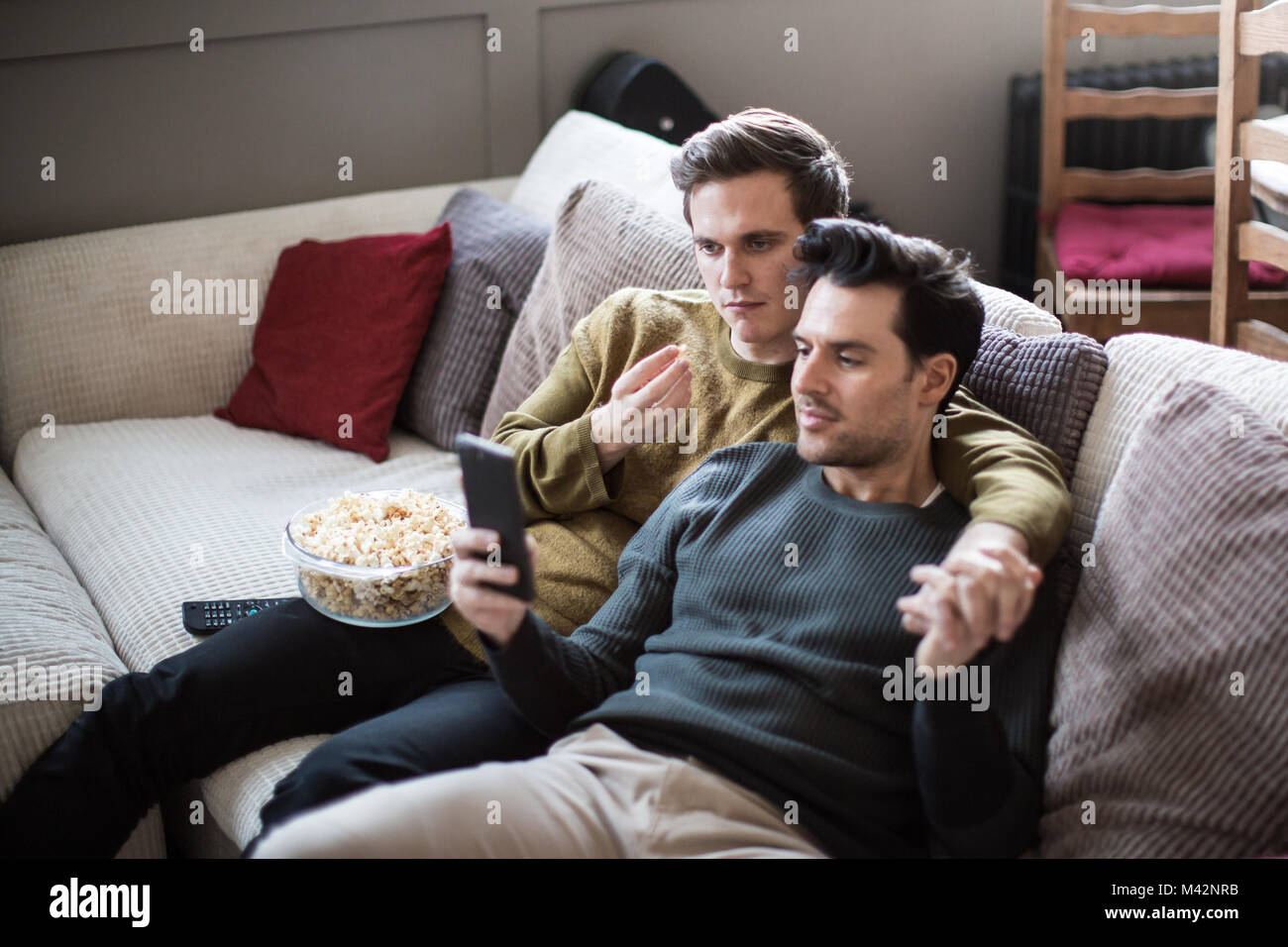 Young male couple relaxing on sofa streaming entertainment Stock Photo