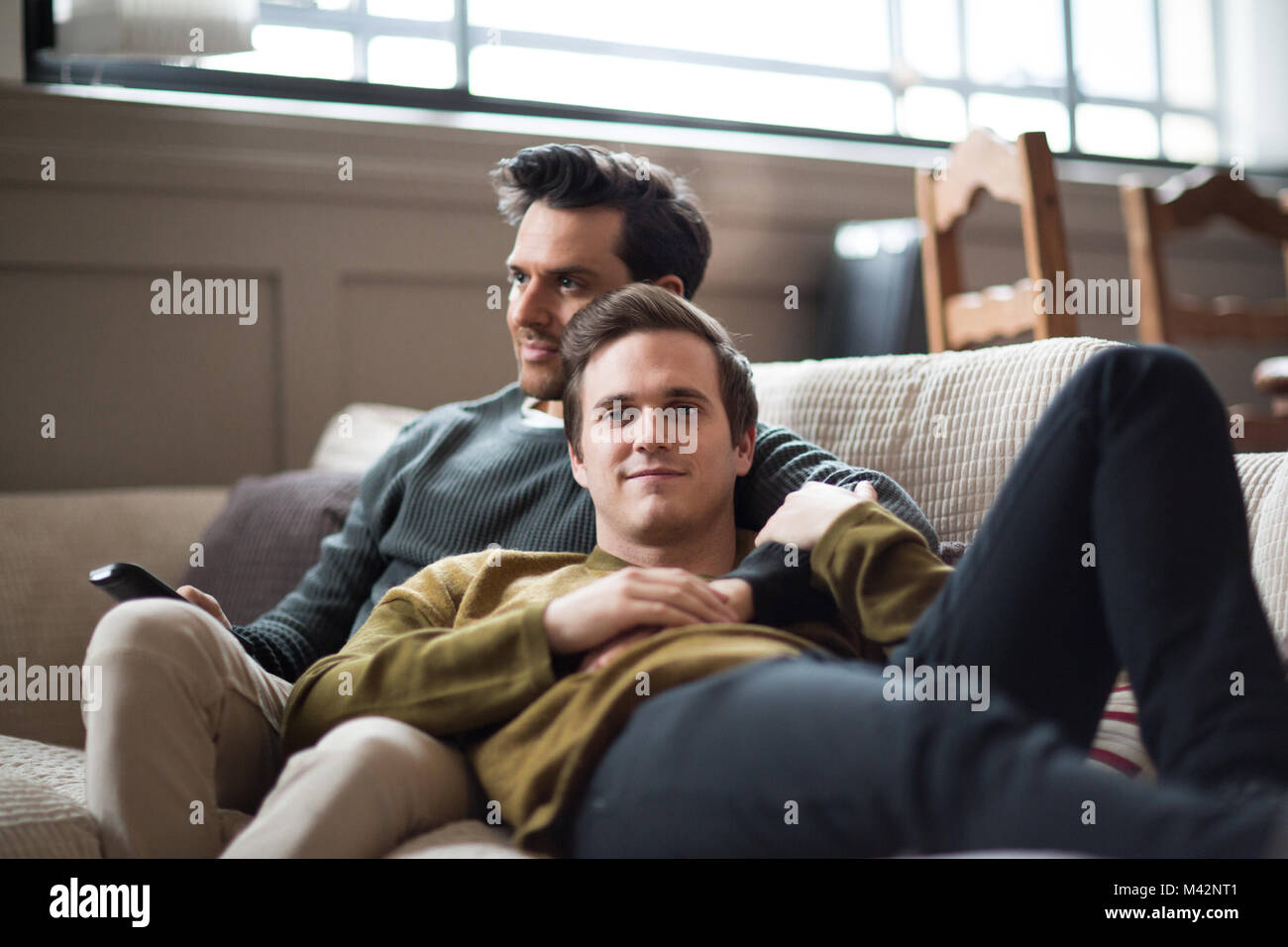 Portrait of young male couple relaxing on sofa Stock Photo