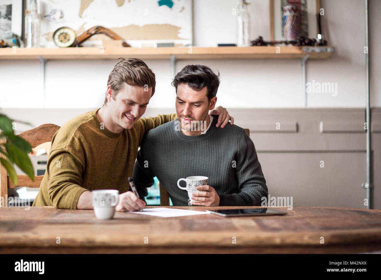 Young male couple signing legal document Stock Photo
