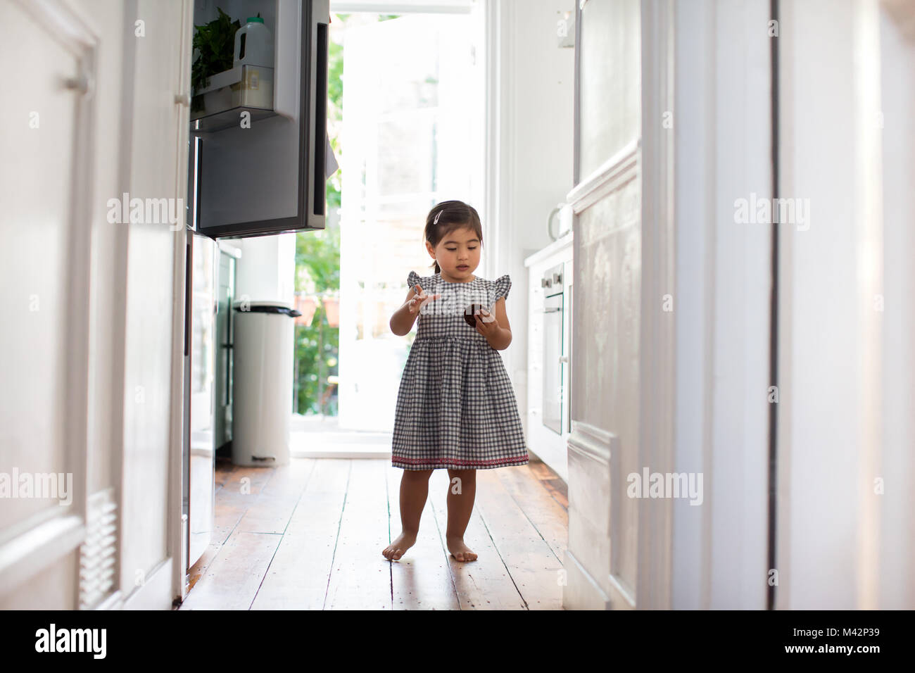 Girl taking a treat from a refrigerator Stock Photo