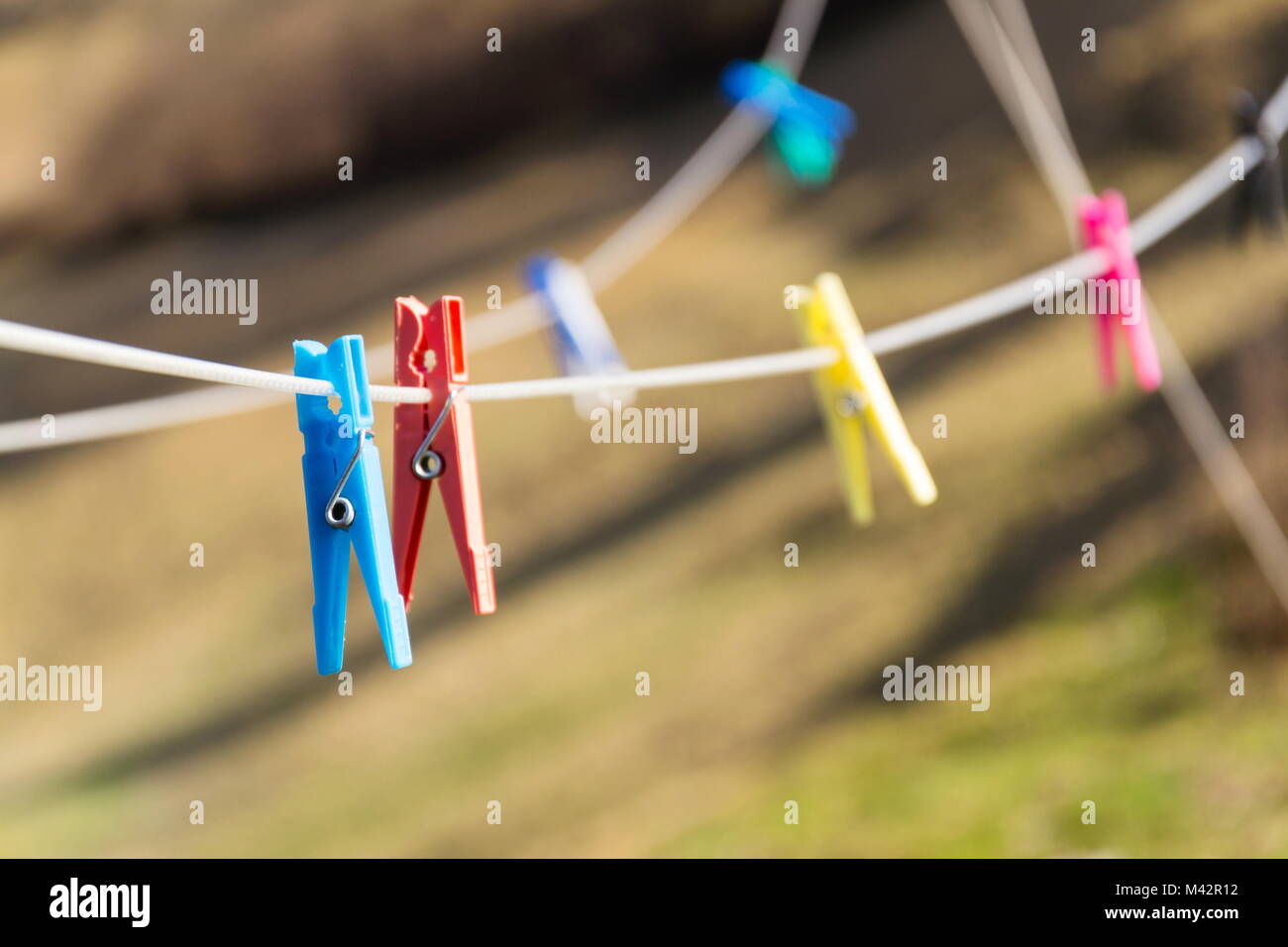 Colorful plastic clothes pegs on white clothesline, fashion business concept Stock Photo
