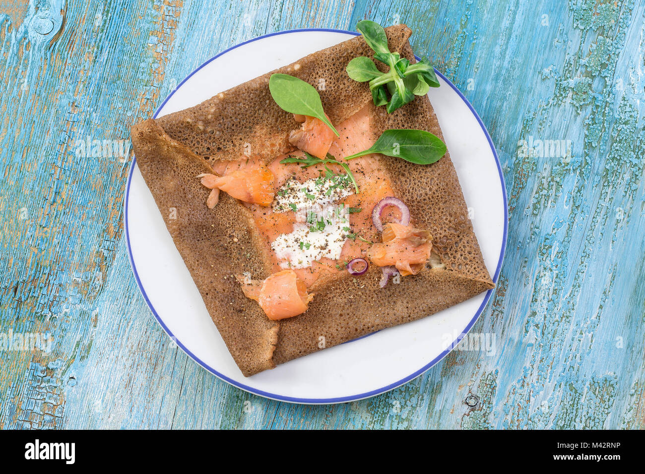 buckwheat crepe with salmon and cheese on blue wooden background Stock Photo