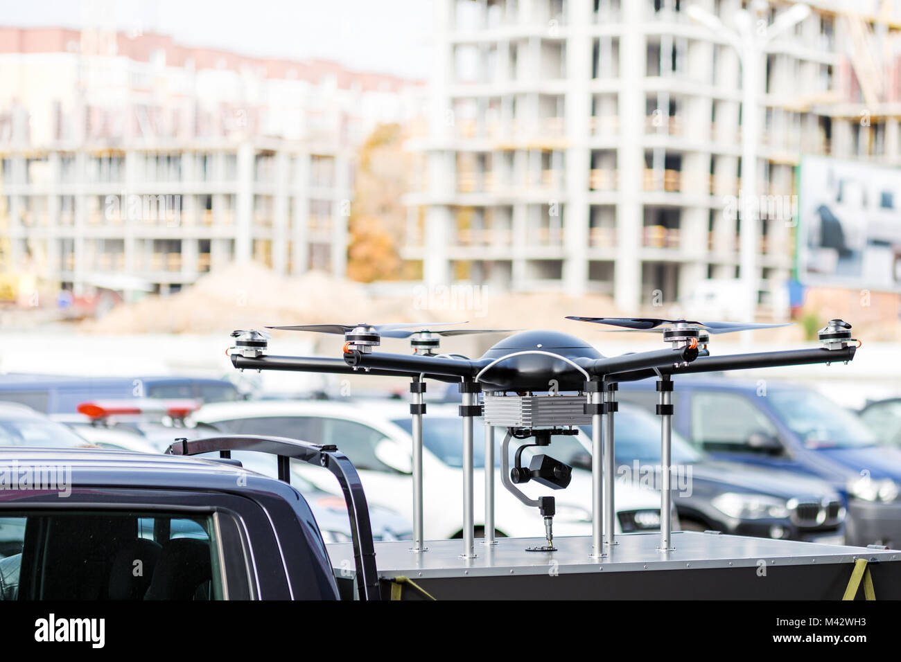 Big custom made drone over picup truck trunk.  Heavy UAV hexacopter with construction site on the background. Commercial aerial photo and video concept Stock Photo