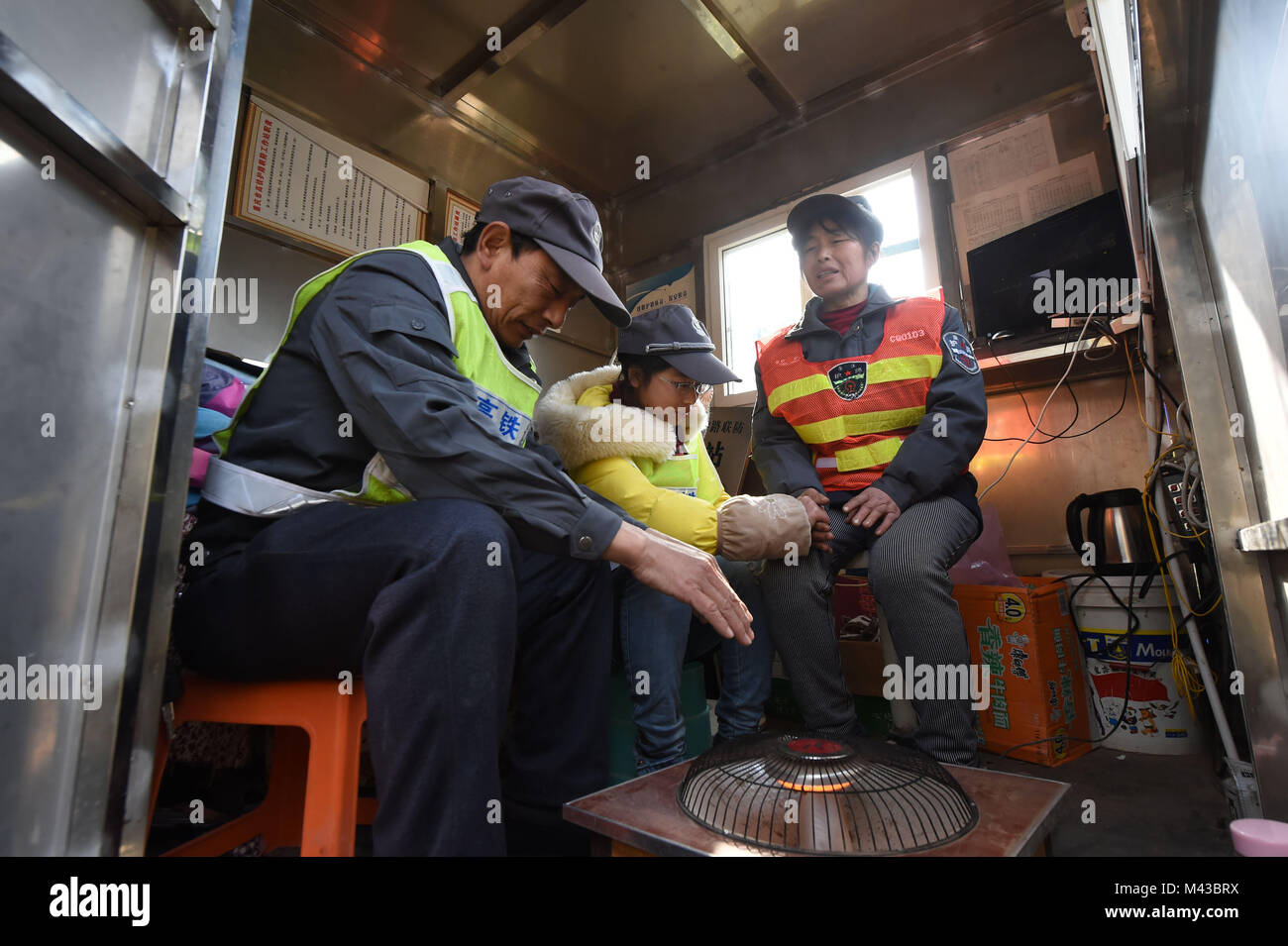 Chongqing, China. 30th Jan, 2018. Railway maintenance worker Liao Xiaocheng (L), his wife Tao Chunxiu and their daughter warm themselves in Lyuchunba Village of Sanjian Town in Fengdu County of Chongqing, southwest China, Jan. 30, 2018. The 50-year-old Liao and his wife Tao Chunxiu, both railway maintenance workers of Lyuchunba section of Chongqing-Lichuan railway line, are responsible for the security of the 6-km-long railway segment here. Credit: Tang Yi/Xinhua/Alamy Live News Stock Photo